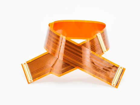 Flexible printed circuit made with orange polyimide film, showing copper traces and connectors in a curved configuration.